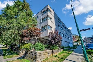 Vancouver apartment for rent - A street view of a residential area with a building, trees, and a sidewalk.