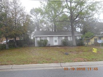 Pensacola house for rent - the front of a white house with a yard and trees