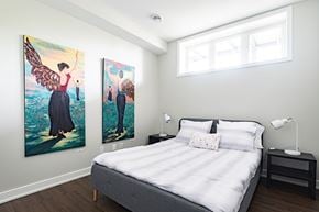 Ottawa apartment for rent - A bedroom with a bed, nightstand, and two paintings on the wall.