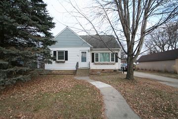 Rochester house for rent - A small house with a grey roof and white siding is surrounded by trees and a sidewalk.