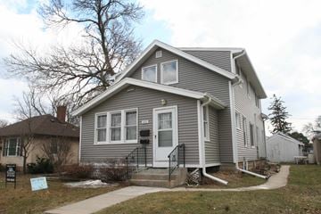Rochester apartment for rent - the front of a gray house with a yard and a sidewalk