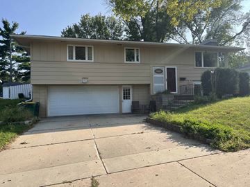 Rochester house for rent - a tan house with a driveway and a white garage door