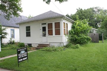 Rochester house for rent - A small white house with a black sign in front that says "For Rent".
