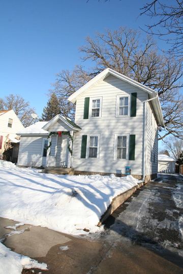 Rochester apartment for rent - A white house with green shutters and a snow-covered ground.