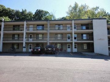 Rochester apartment for rent - A parking lot in front of a multi-story apartment building with two cars parked.