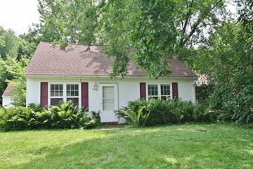 Rochester house for rent - A small white house with red trim and a red door numbered 368 is surrounded by greenery.