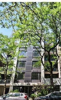 Brooklyn apartment for rent - A modern building with a glass facade is surrounded by trees.