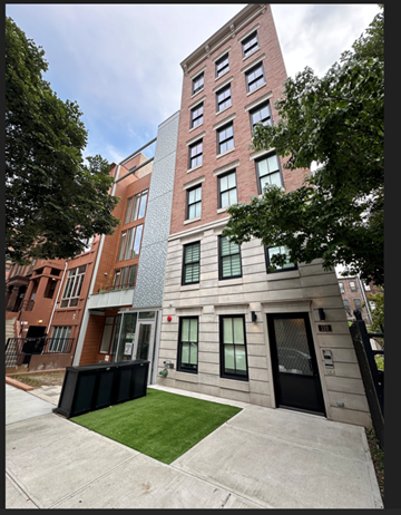 New York apartment for rent - A modern building with a red brick facade and a grey concrete structure in front.