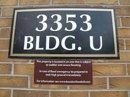 Boulder apartment for rent - A sign on a brick wall that reads "3353 BLDG. U" and includes a warning about flood emergencies.