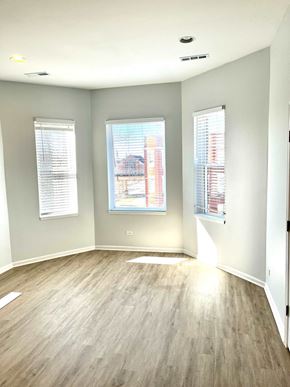Chicago apartment for rent - an empty living room with wood floors and three windows