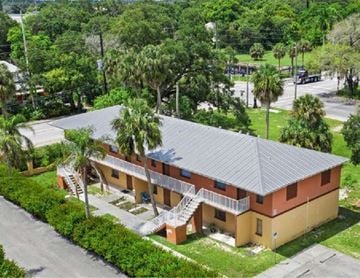 Fort Myers apartment for rent - an aerial view of a yellow house with a gray roof and palm trees