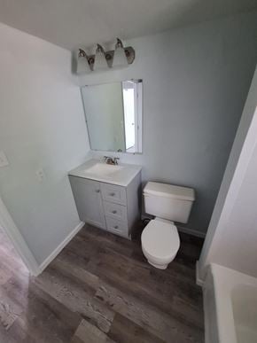 Fort Myers apartment for rent - A white toilet sits in a bathroom next to a sink and mirror.