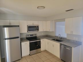 Fort Myers apartment for rent - A kitchen with a refrigerator, microwave, oven, and sink.