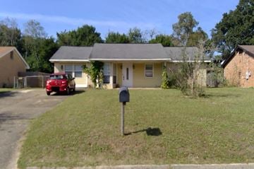 Pensacola house for rent - a house with a mailbox and a red car parked in the driveway
