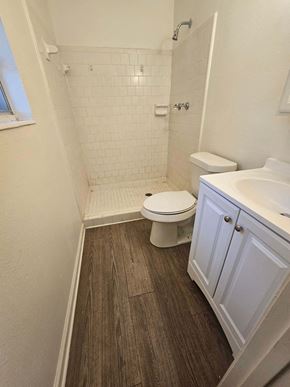 Pensacola house for rent - A white toilet sits in a bathroom with a white sink and a white tiled shower.