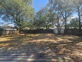 Pensacola house for rent - A backyard with a wooden deck and trees.