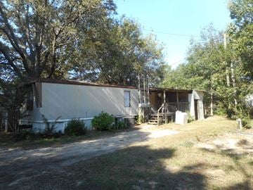 Pensacola house for rent - a mobile home in a yard with trees and a driveway