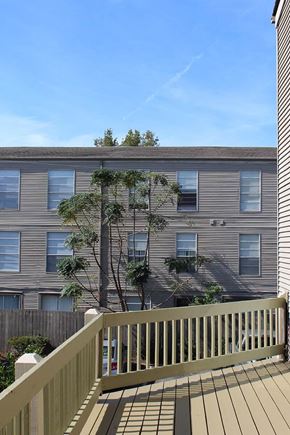 Metairie townhouse for rent - A building with a brown siding and a balcony with a railing.