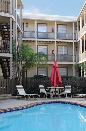Metairie townhouse for rent - A pool with chairs and an umbrella in front of a building.