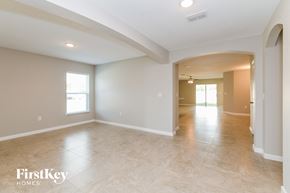 Davenport house for rent - A spacious room with beige walls and flooring, and a large archway leading to another room.
