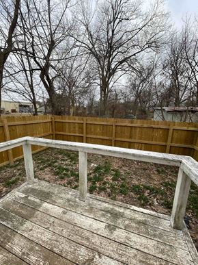 Jonesboro apartment for rent - A wooden deck with a railing and trees in the background.