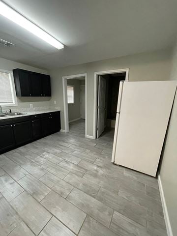 Jonesboro apartment for rent - A kitchen with a white refrigerator and black cabinets.