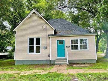 Jonesboro house for rent - A small house with a blue door is surrounded by trees.