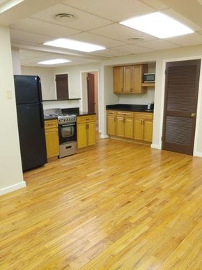 Pittsburgh apartment for rent - an empty kitchen with wooden floors and a black refrigerator