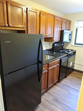 Pittsburgh apartment for rent - a kitchen with wooden cabinets and a black refrigerator