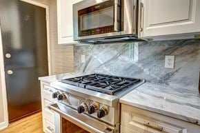 Richmond apartment for rent - A modern kitchen with a stove top oven and microwave above it.