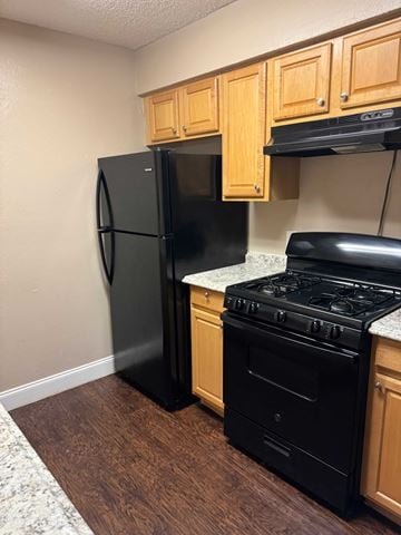 Hubbard apartment for rent - A black fridge and stove in a kitchen with wooden cabinets.