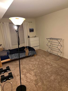 Holland apartment for rent - A bedroom with a bed, a dresser, a lamp, and a pair of dumbbells on the floor.
