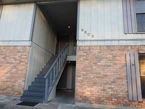 Bay City apartment for rent - A staircase leads to a doorway in a building with the number 6303 on the wall.