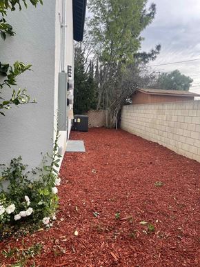 Granada Hills apartment for rent - a side yard with a brick wall and mulch next to a house