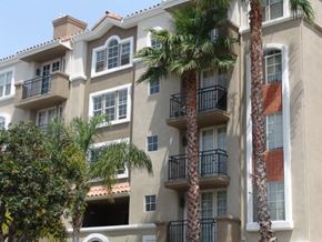 Los Angeles apartment for rent - A building with balconies and palm trees in front.