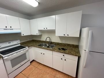 Lake Worth apartment for rent - A kitchen with white cabinets and a granite countertop.