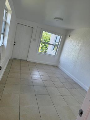 Fort Myers apartment for rent - A room with a white door and a window with a view of trees.