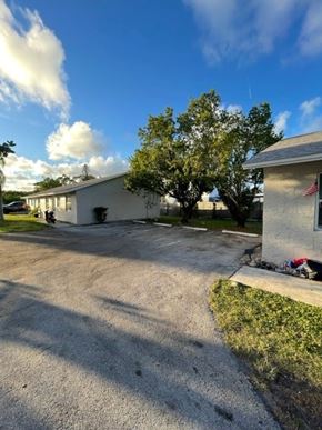 Lake Worth apartment for rent - A white building with a flag on the right side and a tree in front of it.