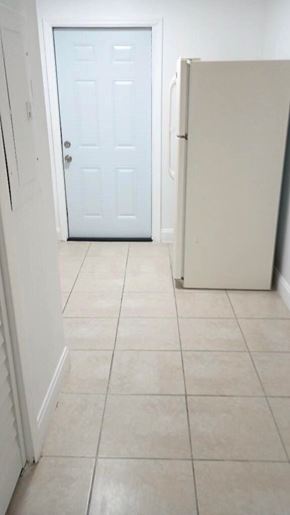 West Palm Beach apartment for rent - A white door is in a hallway with a white fridge.