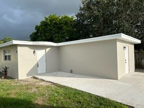 Lake Worth apartment for rent - A small white building with a grey roof and a concrete driveway in front.