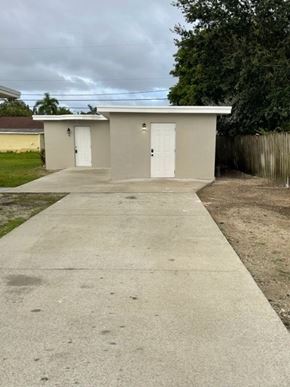 Lake Worth apartment for rent - A concrete pathway leads to a small building with two doors.