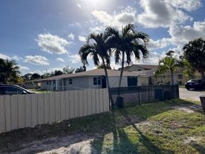 West Palm Beach apartment for rent - A sunny day with palm trees and a house in the background.