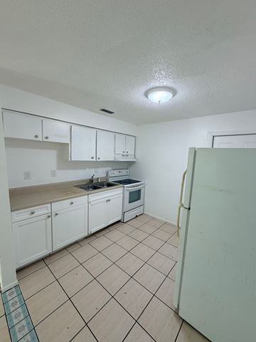 Fort Myers apartment for rent - A kitchen with white cabinets and a white refrigerator.