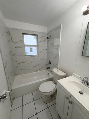 Fort Myers apartment for rent - A white bathroom with a marble wall and a white toilet.