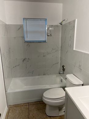 Fort Myers apartment for rent - A white toilet sits in a bathroom with marble tile walls.