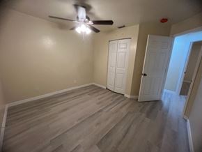 Lehigh Acres apartment for rent - A room with a ceiling fan and light fixture, wooden flooring, and two white doors.