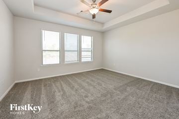 Beaumont house for rent - a living room with carpet and a ceiling fan