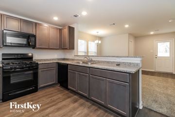 Splendora house for rent - A kitchen with dark wood cabinets and a black stove top oven.