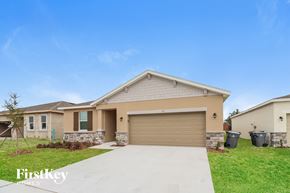 Bartow house for rent - a beige house with a driveway and a garage door