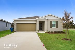 Bartow house for rent - a beige house with a driveway and a garage door